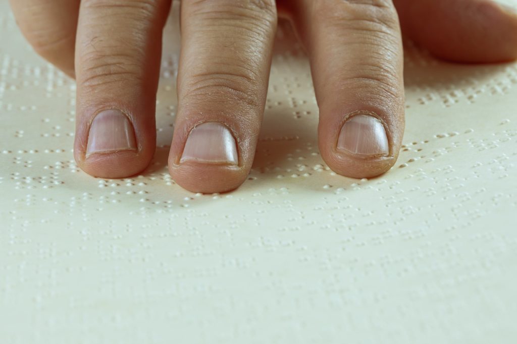 Image of white hand over Braille document