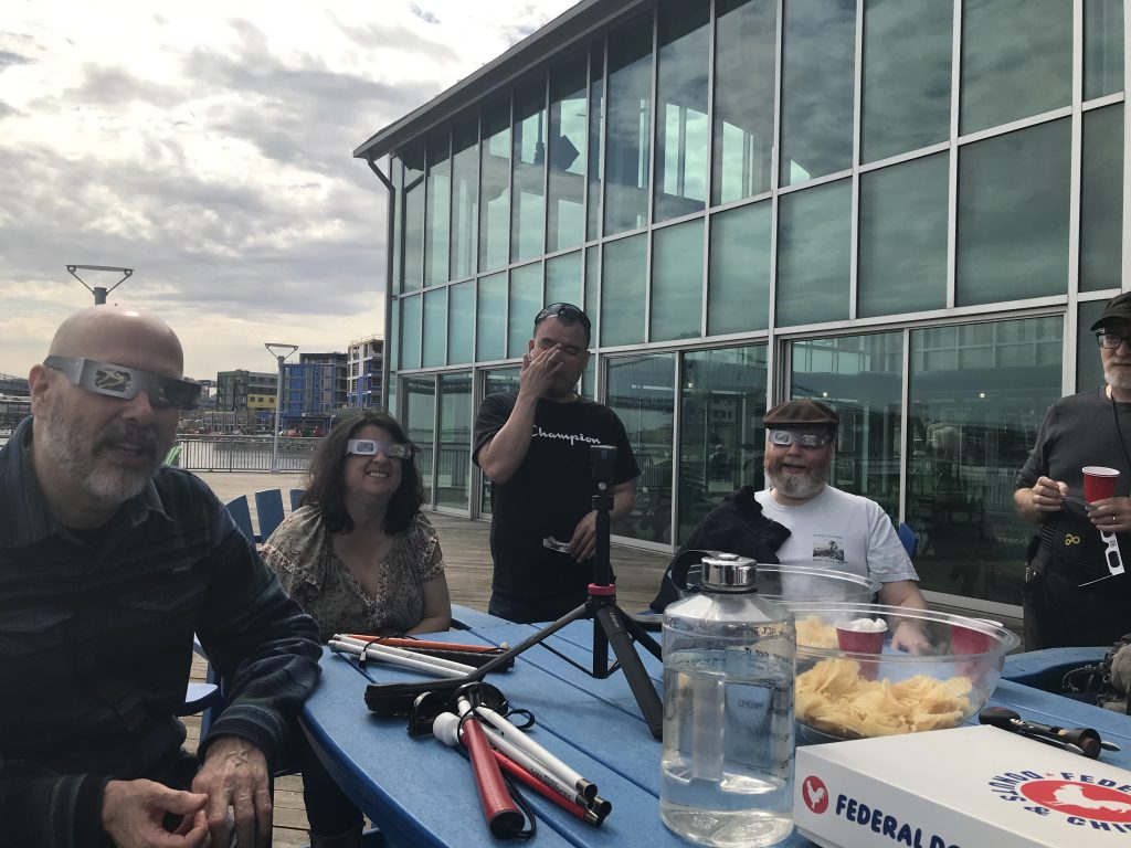 David, Katie, Peter and Ryan smiling and wearing eclipse glasses